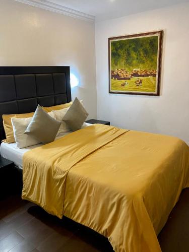 a bedroom with a large bed with a yellow bedspread at Stylish Modern Elegance Deluxe Suite in Lagos