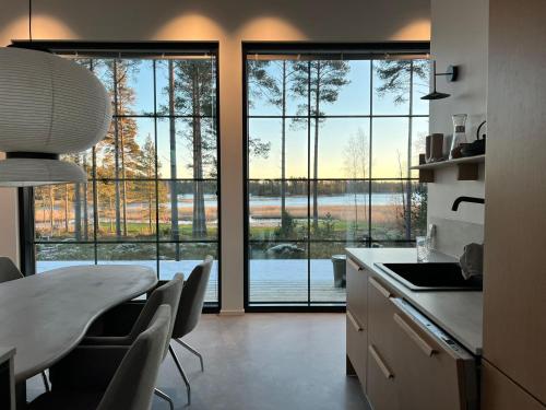een keuken met een tafel en stoelen en een groot raam bij New Seaside Villa with Beach Sauna and Panoramic Views in Porvoo