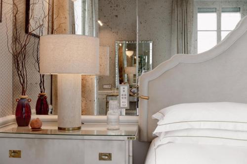 ein Schlafzimmer mit einem Bett und einem Tisch mit einer Lampe in der Unterkunft Hotel d'Angleterre in Genf