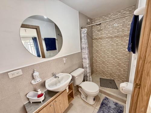 Un baño con lavabo, inodoro y espejo. en Ideal para familia de 5, en Ibarra