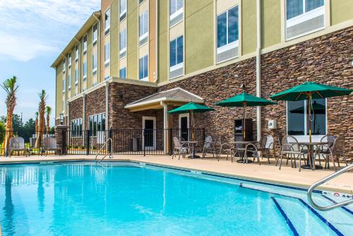 a swimming pool in front of a hotel with chairs and umbrellas at Comfort Inn & Suites Valdosta I-75 in Valdosta