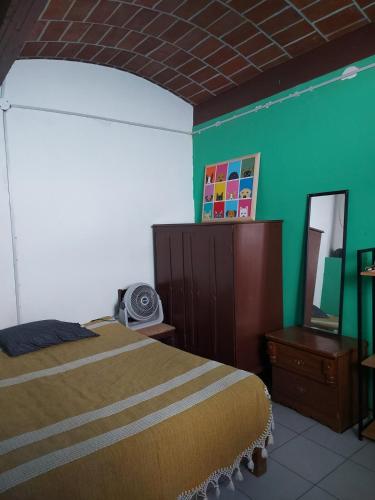 a bedroom with a bed and a green wall at In Oaxaca Casa RodSa in San Agustin de las Juntas