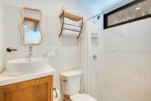 a bathroom with a sink and a toilet and a mirror at 5 Lofts En La Paraiso in Playa Grande