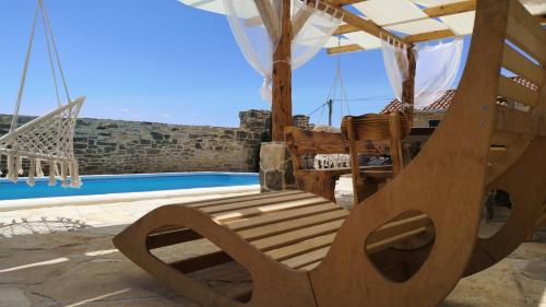 een houten schommel naast een zwembad bij Juniper Stone Cottage by Villas Guide in Alavanja