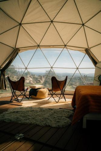 a room with two chairs and a bed in a tent at A Cozy Fireside Glamping Escape with Ridge Views in Fallbrook
