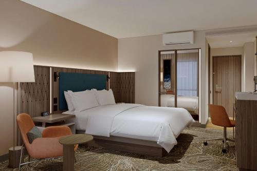 a bedroom with a large white bed and a chair at Courtyard by Marriott Guadalajara Andares in Zapopan