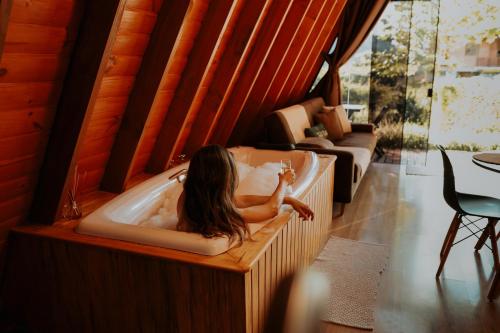 Cabana Amélia, em Gramado في غرامادو: فتاة مستلقية في حوض الاستحمام في غرفة