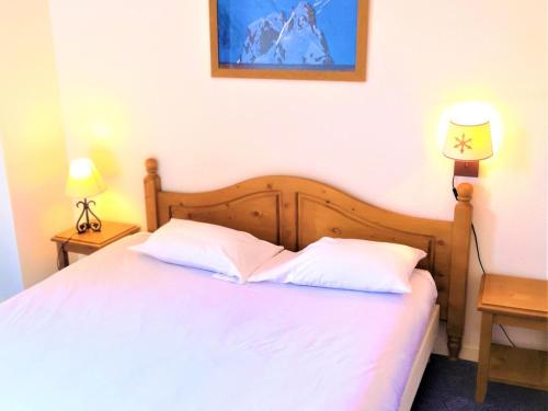 een slaapkamer met een bed met witte lakens en 2 lampen bij Chalet Mitoyen 3 Pièces 7 Pers. avec Piscine et Sauna - Résidence Les Flocons du Soleil - FR-1-863-13 in Le Dévoluy