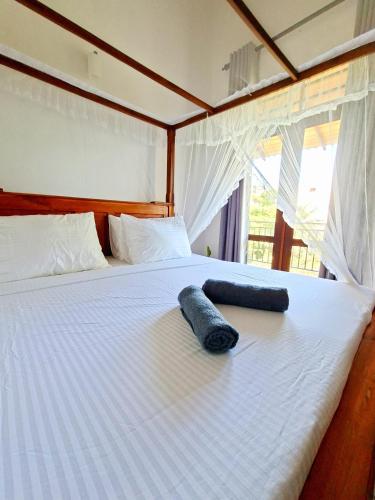 a large white bed with a blue pillow on it at Mangrove Inn Mirissa in Kamburugamuwa