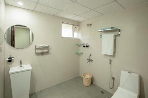 Encanto Farmstay Resort في ميسور: حمام ابيض مع مرحاض ومرآة