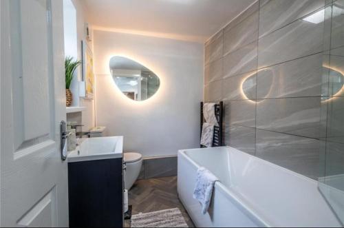 a bathroom with a tub and a toilet and a mirror at Telford Family 3 Bedroom Retreat in Oakengates
