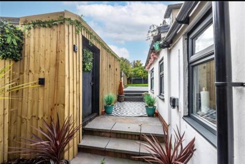 a house with a wooden fence and potted plants at Telford Family 3 Bedroom Retreat in Oakengates