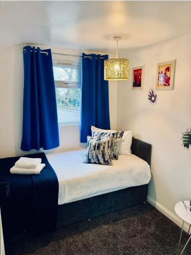 a bed in a room with blue curtains at Telford Family 3 Bedroom Retreat in Oakengates