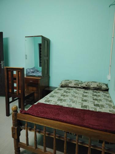 a bedroom with a bed and a dresser and a mirror at JANATHA home stay in Varkala