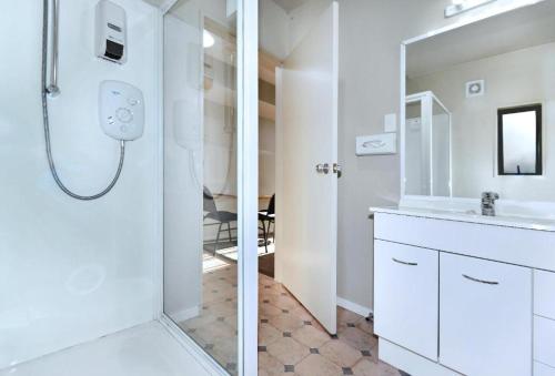a white bathroom with a shower and a sink at Anika Motel in Christchurch