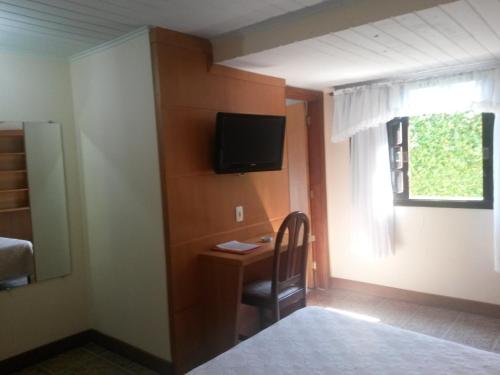 a room with a desk with a television and a window at Hotel Girassol in Penedo