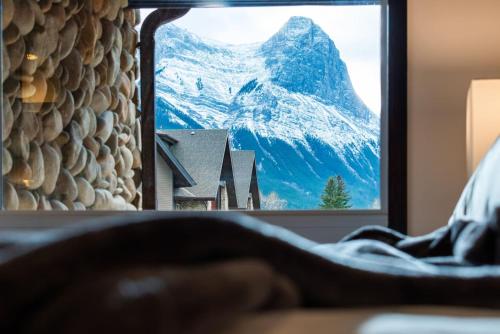 キャンモアにあるRenovated Haven in Rockies with Hot Tub and Poolの鏡に映った雪に覆われた山の姿