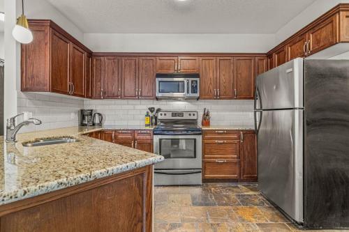 een keuken met houten kasten en een roestvrijstalen koelkast bij Rockies Getaway Condo With Mountain View in Canmore