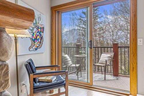 een kamer met een balkon met een stoel en een glazen deur bij Rustic Creekside Retreat 2BR with Stunning View in Canmore