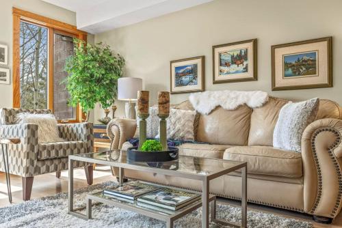 een woonkamer met een bank en een tafel bij Rustic Creekside Retreat 2BR with Stunning View in Canmore