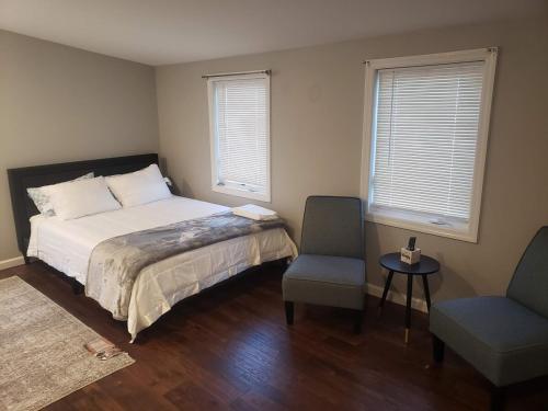 a bedroom with a bed and a chair and two windows at Attractive and Cozy Apartment - 4 bdrms 2 bths in Paterson