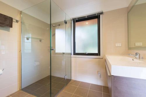 een badkamer met een glazen douche en een wastafel bij Brumbies Run Touchdown Cottages in Jindabyne
