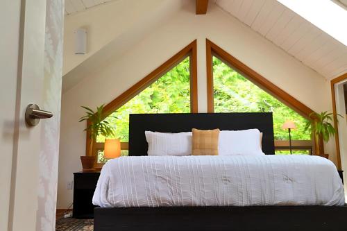 a bedroom with a bed with a large window at Cedar and Salt - By the beach with hot tub and sauna in Tofino