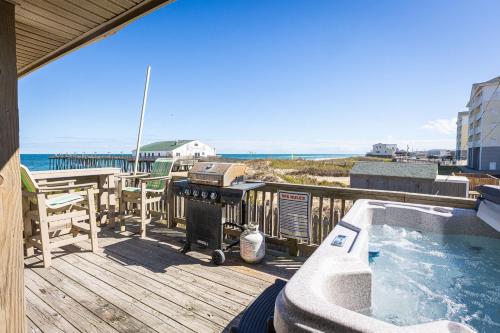 a deck with a hot tub and a table and chairs at Oceanfront Private Beach Access & Community Pool in Kitty Hawk Beach