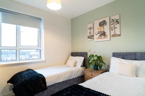 two beds in a room with two windows at Apt - Stay 6 - Stadium View - Coo-op Live Arena in Manchester