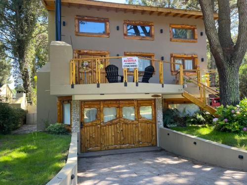 ein Haus mit einem Balkon und einer Terrasse darauf in der Unterkunft Cabañas en Valeria del Mar in Carilo