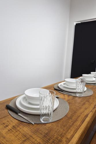 Studio Privativo 3 min Centro para 4 pessoas com 2 quartos ar condicionado في أبرلانديا: طاولة خشبية عليها صحون واكواب