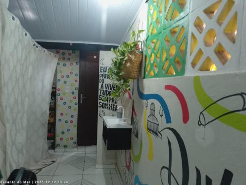 baño con lavabo y pared cubierta de graffiti en Pousada Recanto do Mar, en Tutóia