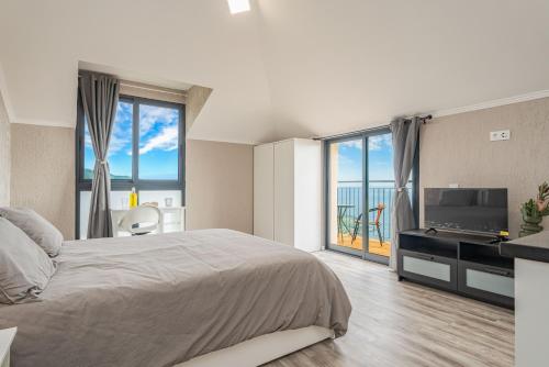 a bedroom with a bed and a television and a balcony at Madeira Sunrise Villa in Gaula