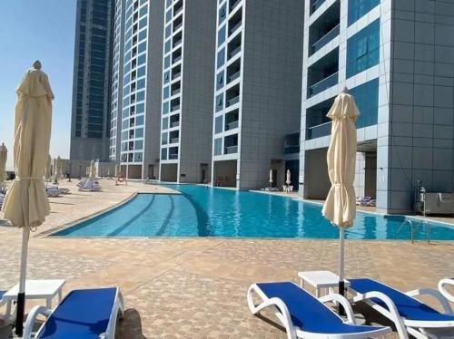 una piscina con lettini e ombrelloni di Ajman Corniche Residence ad Ajman