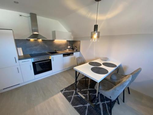 eine Küche mit weißen Schränken und einem Tisch mit Stühlen in der Unterkunft 2 Zimmer-Wohnung ruhig modern zentrumsnah in Abensberg