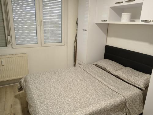 Un dormitorio pequeño con una cama y dos ventanas. en Apartman Centar 2, en Šabac