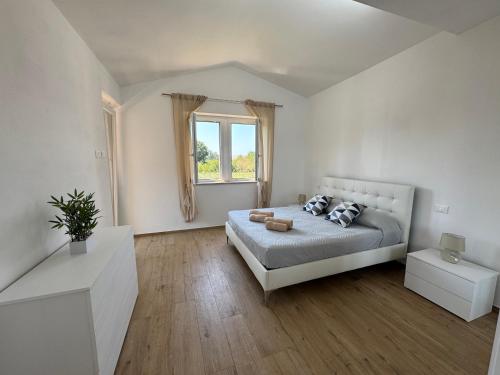 een witte slaapkamer met een bed en een raam bij Il Casalone in Ponte a Tressa