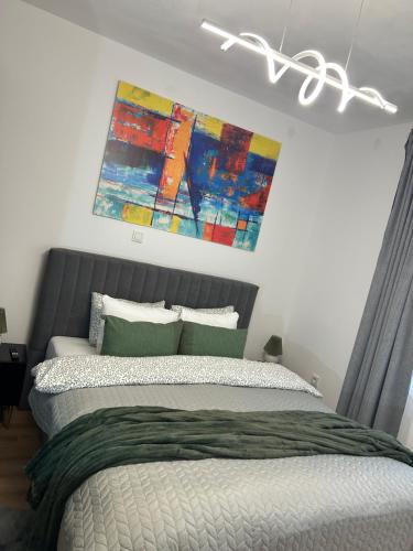 a bedroom with a bed with a painting above it at Apartmani Bjelovar - Centar 4 in Bjelovar