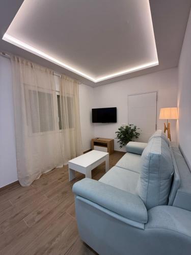a living room with a blue couch and a tv at Apartamento LORETO - Hotel Ruta del Segur in Pontones