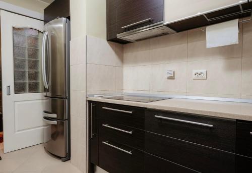 a kitchen with black cabinets and a stainless steel refrigerator at Downtown Cozy Retreat - parcare inclusa in Vatra Dornei