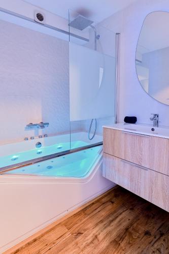 a bathroom with a tub and a sink and a mirror at Mini-duplex NOLEMMA - splendide vue mer, balneo et parking in Deauville