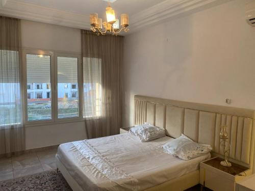 a bedroom with a bed and a chandelier at Luxe & Sérénité Sahloul 4 in Sousse