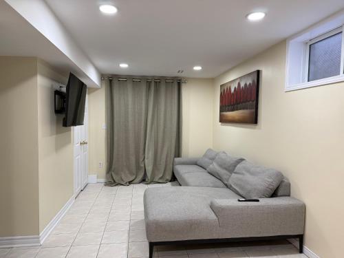 ein Wohnzimmer mit Sofa und Fernseher in der Unterkunft Luxury suit Walkout Basement with open Patio in Guelph