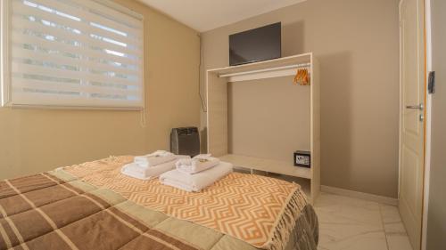 Un dormitorio con una cama con dos toallas encima. en Departamentos Turísticos MD, en El Calafate