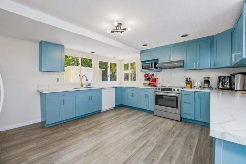 a large kitchen with blue cabinets and white appliances at Marbella Lane - Luminous Seascape Ocean View in Malae