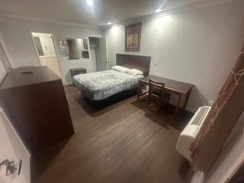 a small bedroom with a bed and a desk and a table at Heritage Inn in Pomona