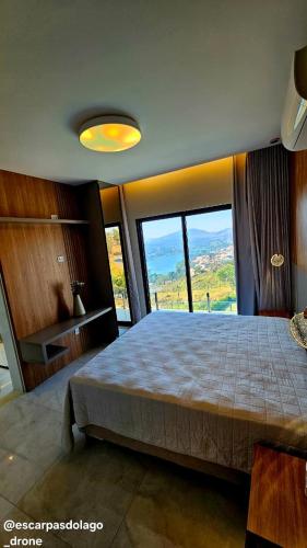 a bedroom with a large bed with large windows at Casa Amaral in Capitólio