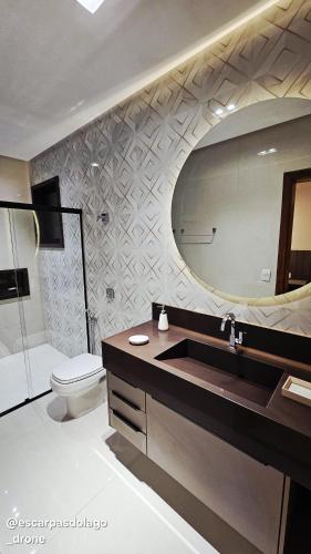 a bathroom with a sink and a toilet and a mirror at Casa Amaral in Capitólio