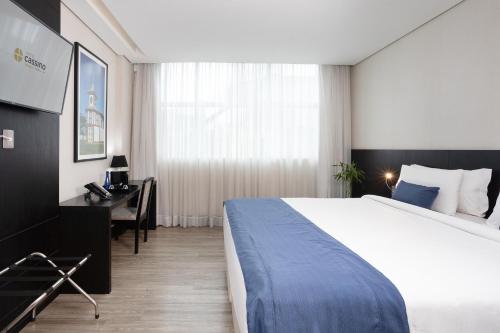 een hotelkamer met een groot bed en een bureau bij Cassino Tower Savassi - Próximo a FIEMG in Belo Horizonte