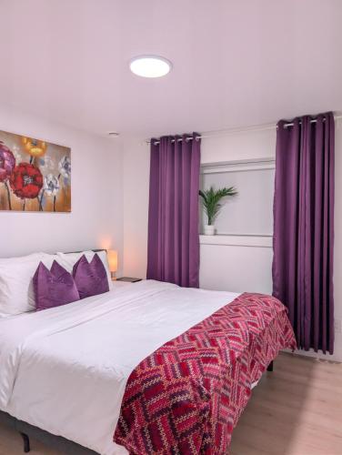 a bedroom with a large bed with purple curtains at NEST- Modern 2BR Basement Retreat in South Surrey in Surrey
